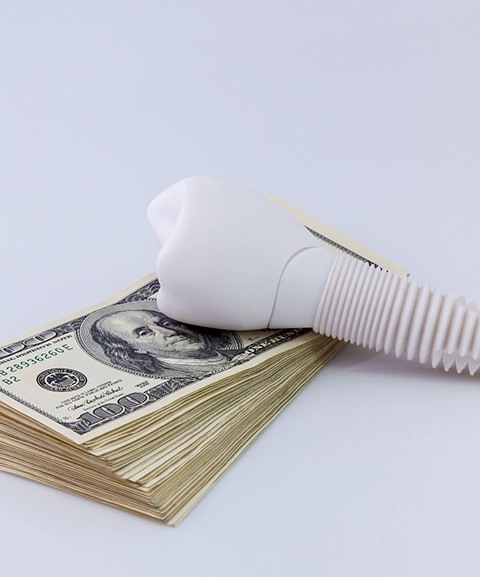 Model of a dental implant resting on top of money