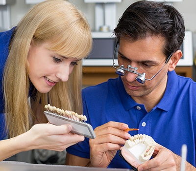 Implant dentist in Mayfield Heights comparing dental shades with assistant