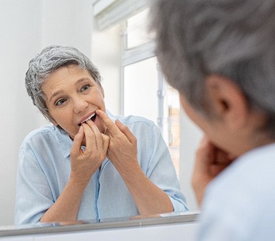 Woman flossing her dental implants in Mayfield Heights