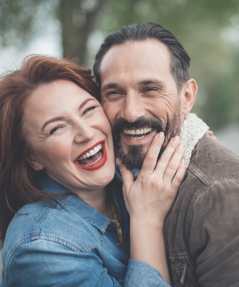 Man and woman smiling together after detnal implant supported tooth replacement