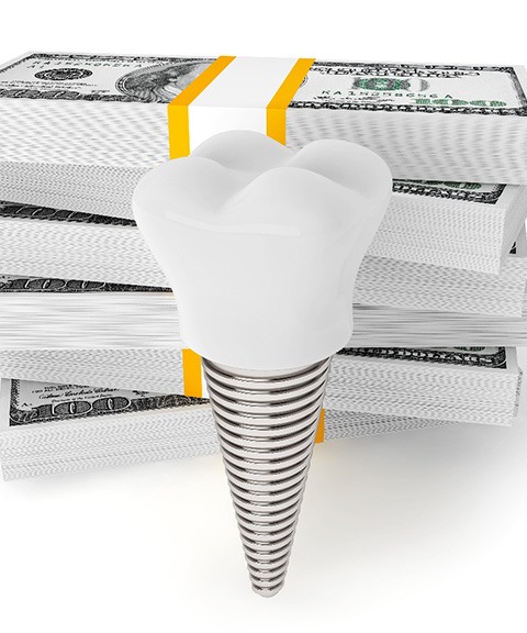 Implant by money stacks representing cost of dental implants in Mayfield Heights