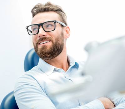 Man with glasses smiling at periodontist’s office