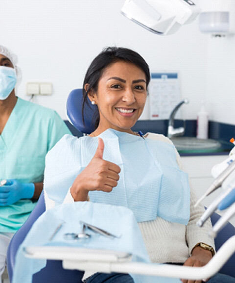 Woman in dental chair giving thumbs up before osseous surgery in Mayfield Heights