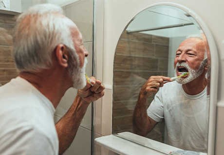 Man brushing his teeth after dental implant surgery in Mayfield Heights