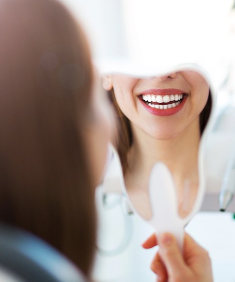 Woman looking at smile after robot assisted dental implant surgery