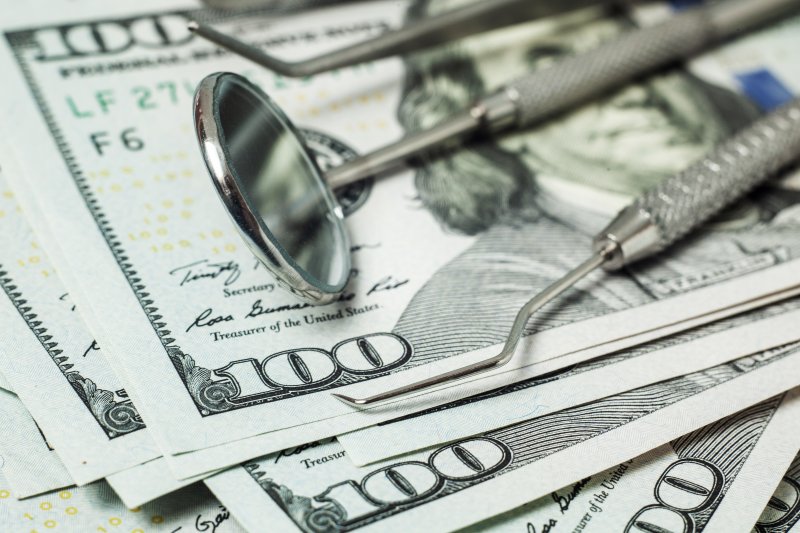 Dental instruments stacked on top of a pile of money